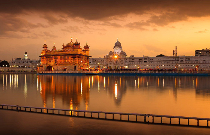 Golden Temple in Amritsar illuminated at sunset, visited by guests on a Luxury Golden Triangle Tour as part of their India Group Tour experience.