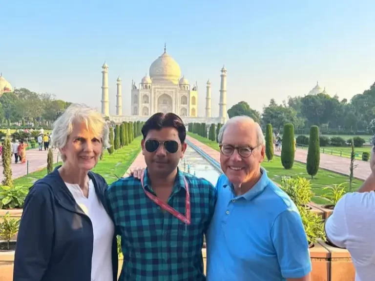 Kevin O'Malley, former U.S. Ambassador, and his wife pose in front of the Taj Mahal with their Indian tour guide during their Luxury Golden Triangle Tour in India.