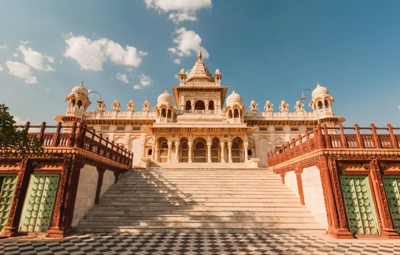 Majestic white marble palace with intricate carvings and domed architecture, set against a clear blue sky.